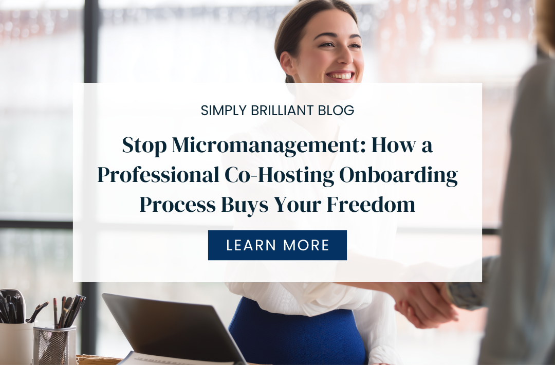 Smiling professional woman in a white blouse shakes hands with another person in a bright office beside a desk with a laptop.